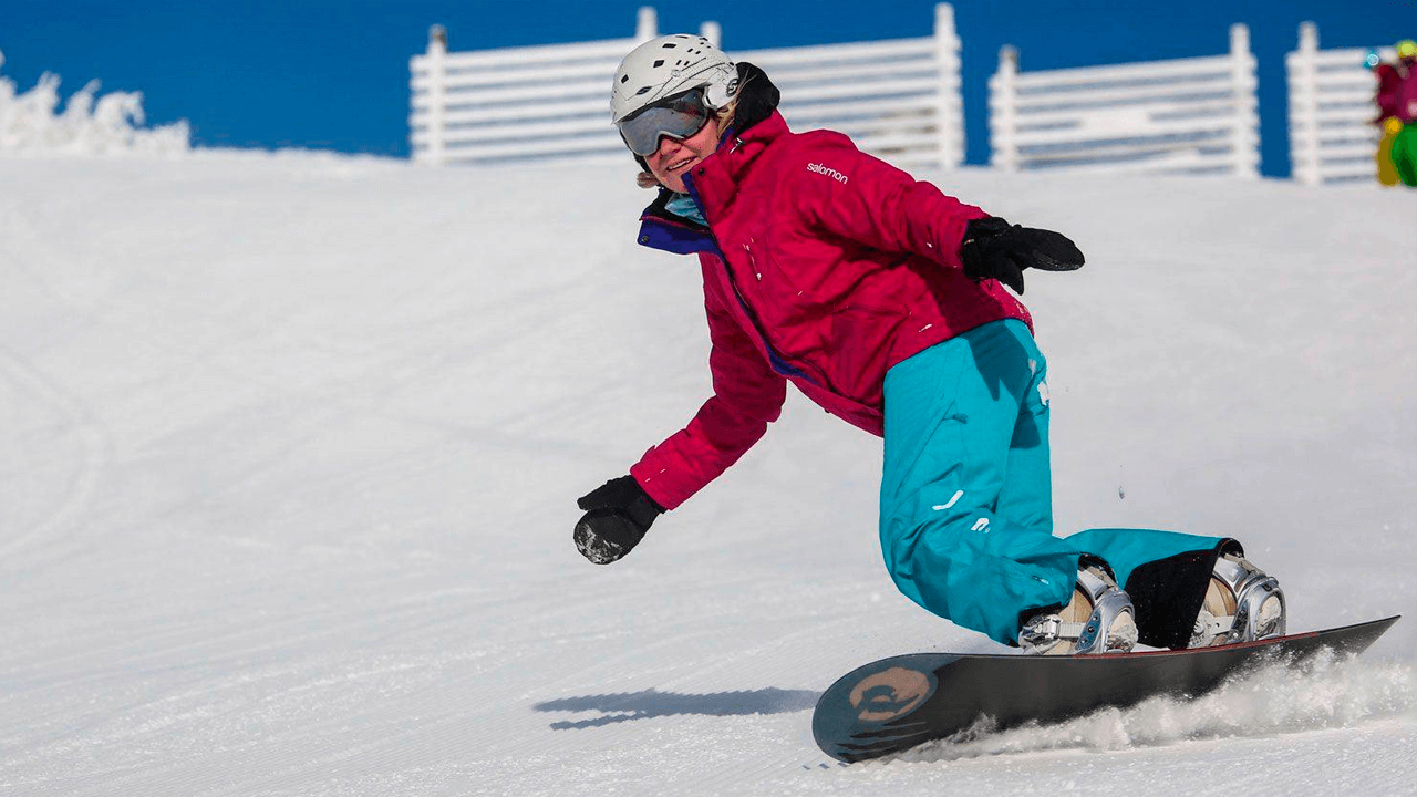 Девушка учится кататься на сноуборде